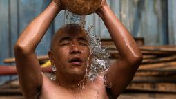 Seorang pendeta mandi suci sebelum mengambil bagian dalam prosesi membawa Seto Machindranath, dewa pelindung Nepal, selama festival kereta di Kathmandu (9/4/2022). (AFP/Prakash Mathema)