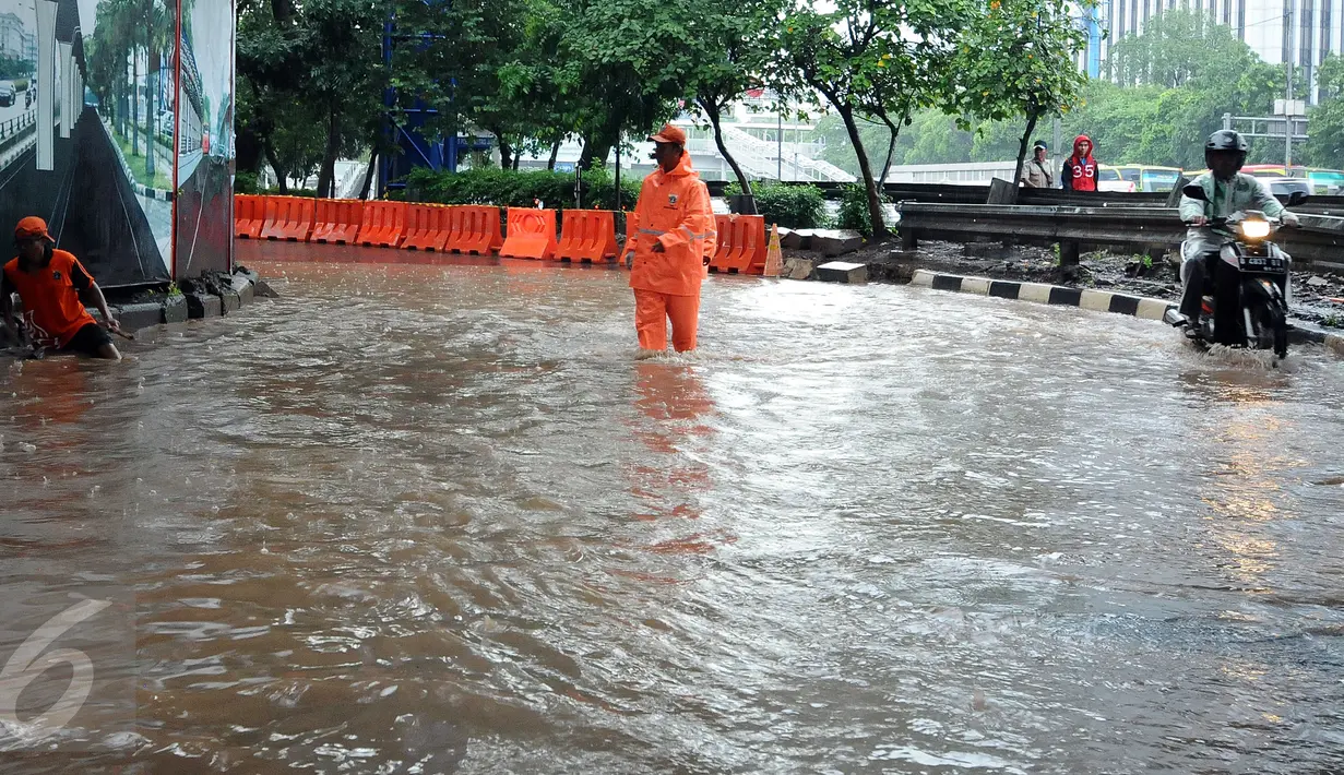 Petugas PPSU Kel Kuningan Barat mencari saluran pembuangan air di putaran kolong fly over Kapt Tendean, Jakarta, Selasa (9/2/2016). Hujan yang mengguyur Jakarta sore ini mengakibatkan putaran ini tergenang air. (Liputan6.com/Helmi Fithriansyah)