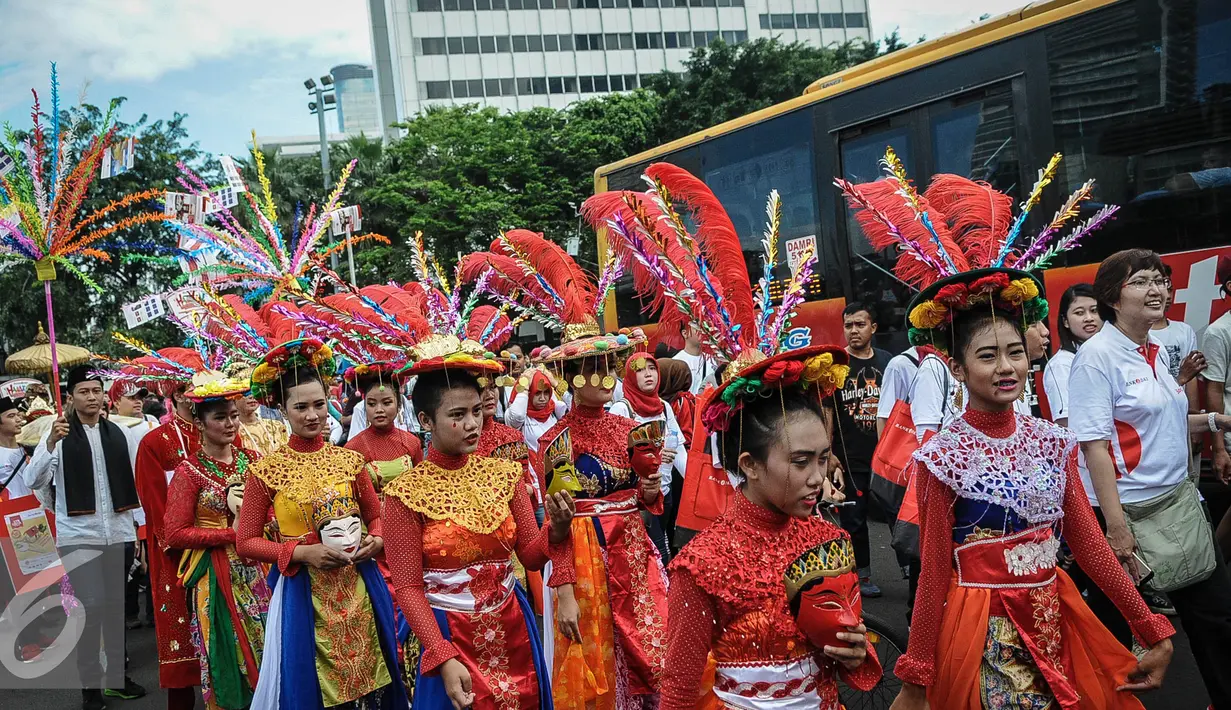 Sejumlah wanita mengenakan busana penari topeng dalam acara Hajatan Bank DKI saat Car Free Day di kawasan Bundaran HI Jakarta, Minggu (16/10). Hajatan Bank DKI ini digelar dalam bentuk karnaval kebudayaan Betawi. (Liputan6.com/Faizal Fanani)