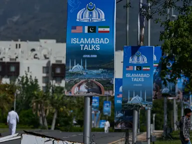 Para pekerja berjalan melewati papan reklame di dekat Hotel Serena, menjelang putaran kedua negosiasi antara Amerika Serikat dan Iran, di Islamabad, Pakistan, Senin 20 April 2026. Hari ini, Senin 20 April 2026, Iran secara resmi menyatakan menolak mengirimkan delegasi untuk melanjutkan perundingan damai tahap dua dengan Amerika Serikat (AS) di Islamabad, Pakistan. (AP Photo/Anjum Naveed)