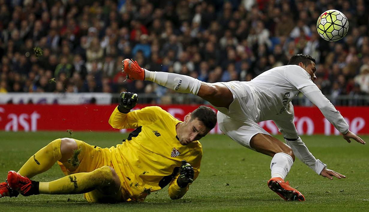 Pemain Real Madrid, Cristiano Ronaldo, berebut bola dengan kiper Sevilla, Sergio Rico, pada laga La Liga Spanyol di Stadion Santiago Bernabeu, Madrid, Minggu (20/3/2016). Gol Madrid dicetak oleh Benzema, Ronaldo, Bale dan Jese. (Reuters/Sergio Perez)