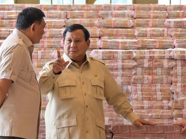 Presiden Prabowo Subianto (tengah) berbicara dengan Jaksa Agung Sanitiar Burhanuddin (kanan) dan Menteri Pertahanan Indonesia Sjafrie Sjamsoeddin di samping tumpukan uang kertas rupiah Indonesia senilai 800 juta USD di gedung Kejaksaan Agung Republik Indonesia, Jakarta, Senin 20 Oktober 2025. (BAY ISMOYO/AFP)