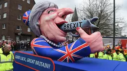 Patung menyerupai PM Inggris Theresa May dengan pistol bertulisan "Brexit" ikut dalam karnaval tradisional 'Rose Monday' di Dusseldorf, Jerman, Senin (27/2). Karnaval 'Rose Monday' berisi sindiran satir para pemimpin dunia. (AFP PHOTO / Patrik STOLLARZ)