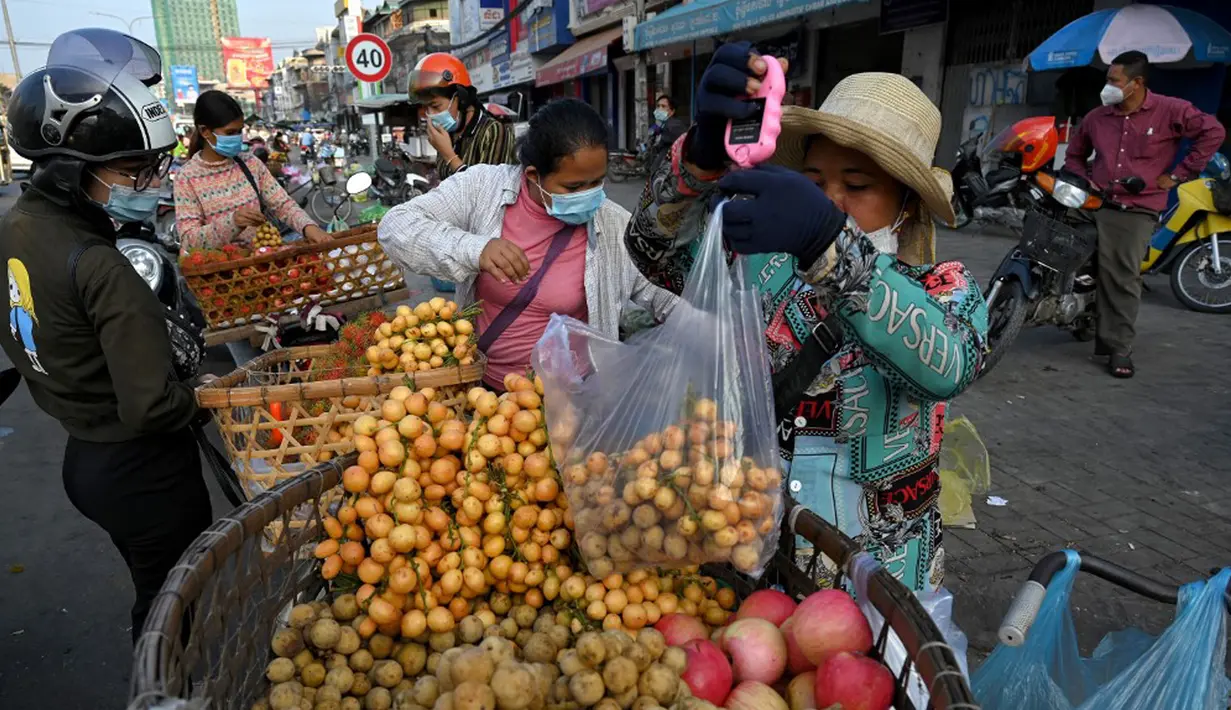 Seorang pedagang menimbang buah di sepanjang jalan karena pasar tetap tutup di tengah pembatasan lockdown yang diberlakukan untuk mencoba menghentikan lonjakan kasus virus corona COVID-19 di Phnom Penh, Kamboja, Selasa (11/5/2021). (TANG CHHIN Sothy/AFP)