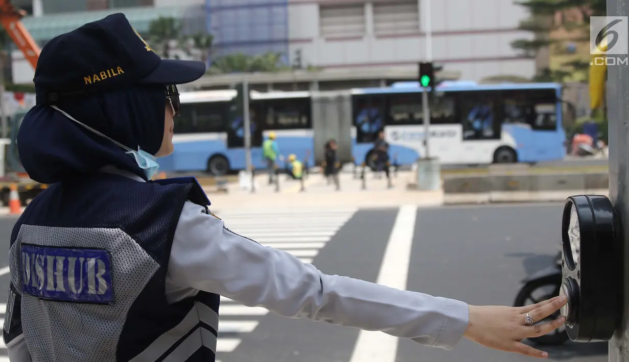 Petugas sedang menekan tombol di pelican crossing di kawasan Thamrin, Jakarta, Minggu (29/7). Pelican crossing di kawasan Thamrin sudah bisa di gunakan pengganti JPO yang akan dibongkar. (Liputan6.com/Herman Zakharia)