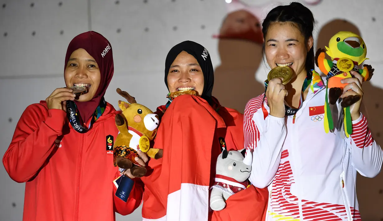 Peraih medali emas Indonesia Susanti Rahayu Aries (tengah), medali perak Indonesia Puji Lestari dan medali perunggu China, He Cuilian berpose pada upacara medali olahraga panjat tebing wanita Asian Games 2018 di Palembang (23/8). (AFP PHOTO / Adek Berry