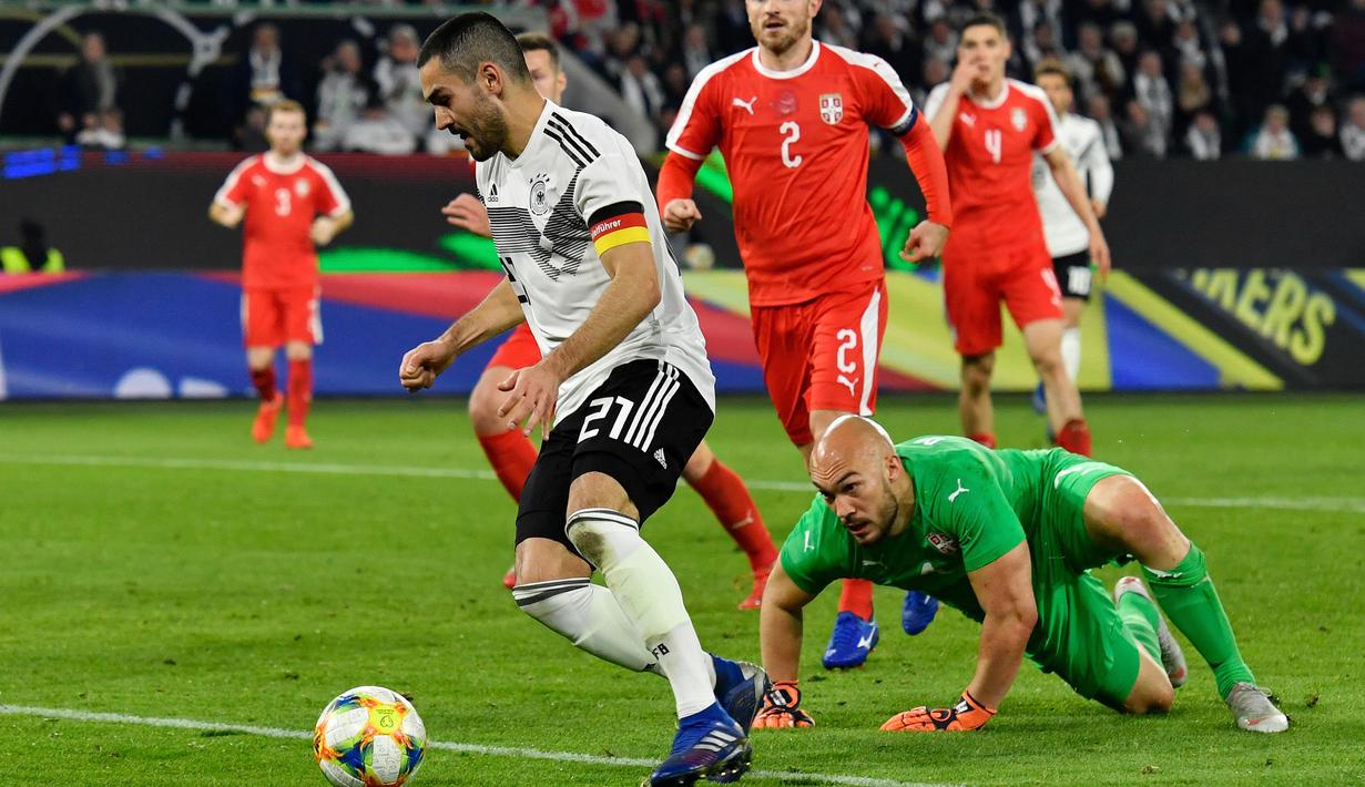 Gelandang Jerman, Ilkay Gundogan, berusaha melewati kiper Serbia, Marko Dmitrovic, pada laga persahabatan di Stadion Volkswagen, Rabu, (20/3). Jerman ditahan imbang 1-1 oleh Serbia. (AFP/John Macdugall)