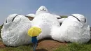 Salah satu pengunjung berdiri di depan kelinci raksasa yang dirancang oleh seniman Belanda Florentijn Hofman dan dipamerkan pada Taoyuan Land Art Festival di Taiwan, (3/9/2014). (REUTERS/Pichi Chuang)