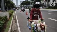 Pedagang kopi keliling saat melintas di Jalan Jenderal Soedirman, Jakarta, Minggu (11/10/2020). Gugus Tugas Percepatan Penanganan Covid-19 mencatat adanya pelambatan kenaikan kasus positif atau aktif di Ibu Kota selama sebulan pemberlakukan PSBB yang diperketat. (merdeka.com/Iqbal S. Nugroho)