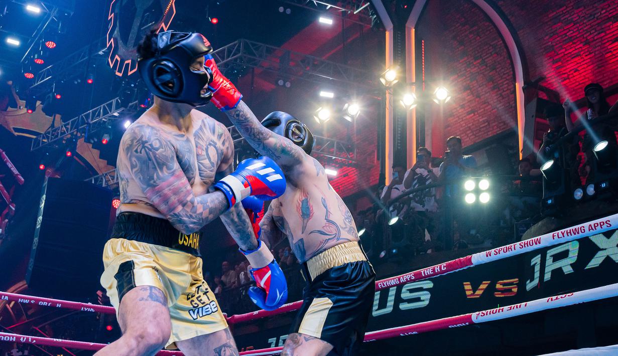 Pemain drum Superman is Dead, Jerinx (kanan), berhasil mendaratkan pukulan di pelipis kiri dari Komika, Uus, dalam pertandingan tinju Holywings Sport Show (HSS) Series 3 yang berlangsung di Atlas Super Club, Bali, Minggu (10/9/2023). (Dok. Holywings)