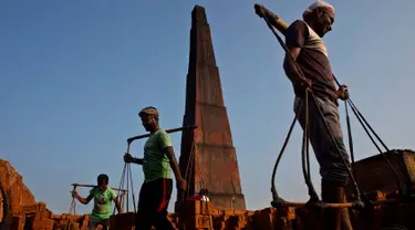 Para pekerja India membawa batu bata di pundak mereka di pabrik pembuatan batu bata di pinggiran Gauhati, India (22/11). Mereka menghasilkan 120 Rupee (kurang dari 2 Dolar) per hari. (AP Photo/Anupam Nath)