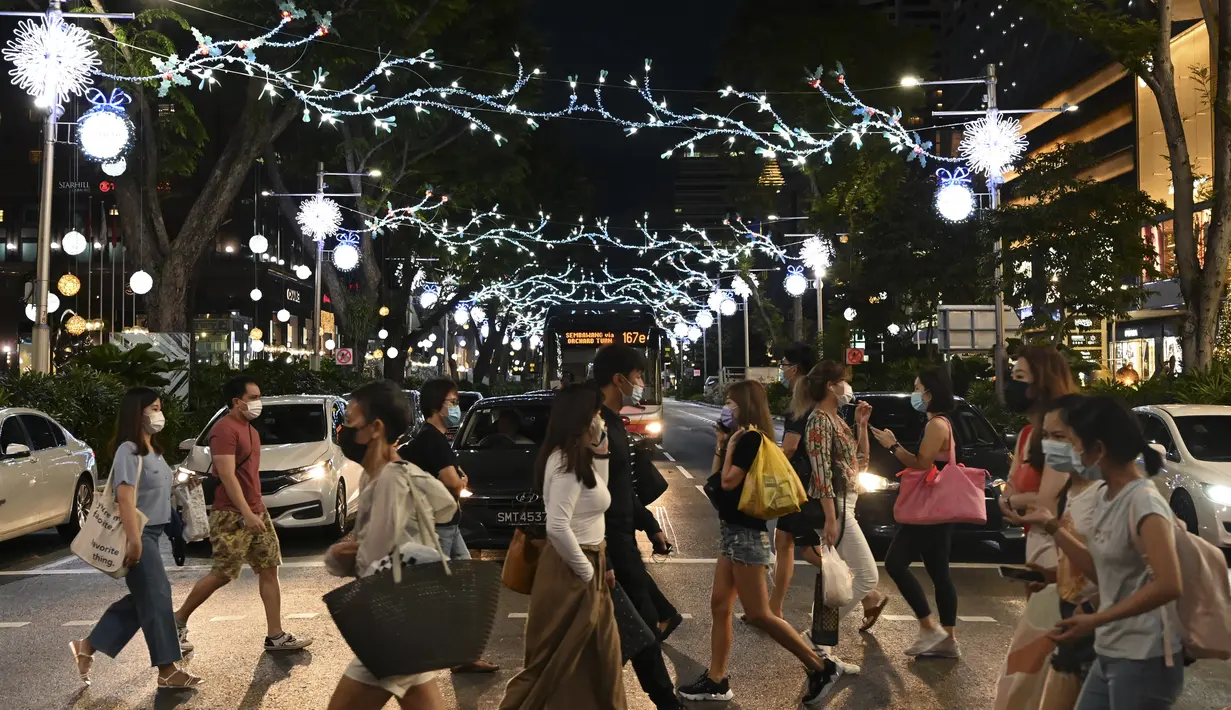 Orang-orang berjalan melewati dekorasi lampu Natal di luar pusat perbelanjaan di sepanjang kawasan Orchard road di Singapura, Selasa (8/12/2020). Mengusung tema Love This Christmas, acara tahun ini lebih sunyi karena aktivitas jalanan dibatasi di tengah pandemi Covid-19. (ROSLAN RAHMAN / AFP)