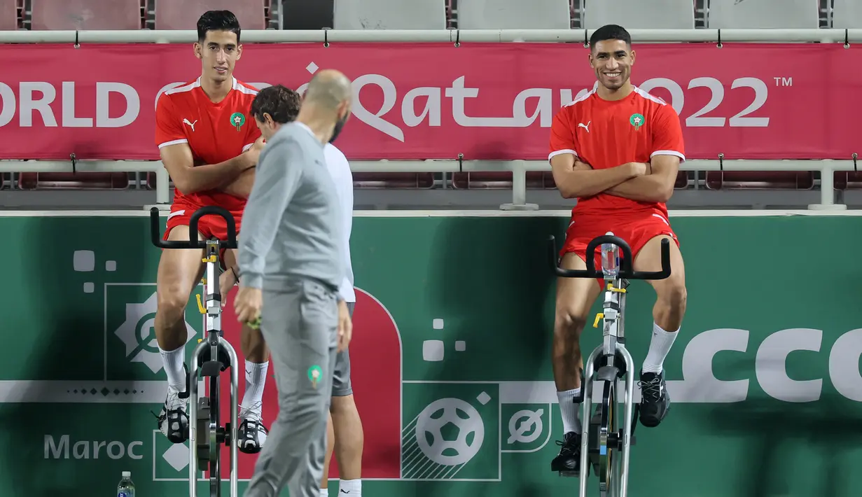 Pelatih Maroko, Walid Reragui (tengah) berbicara dengan bek Achraf Hakimi (kanan) dan Nayef Aguerd selama sesi latihan di Stadion Al Duhail SC di Doha (16/12/2022). Maroko akan bertanding melawan Kroasia untuk memperebutkan juara 3 Piala Dunia 2022. Keduanya dipertemukan kembali setelah pernah bertanding pada babak penyisihan grup F lalu. (AFP/Karim Jafaar)