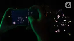 Warga saat memotret Jakarta Lights Festival di Taman Sumenep, Jakarta, Jumat (23/12/2022). Pemprov DKI Jakarta menggelar acara Jakarta Lights Festival sebagai rangkaian perayaan Natal dan Tahun Baru (Nataru) 2023. (Liputan6.com/Herman Zakharia)
