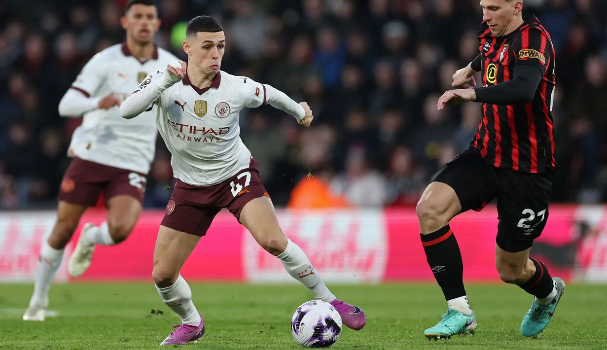 Pemain Manchester City, Phil Foden (kiri) berebut bola dengan pemain Bournemouth, Illia Zabarnyi pada laga lanjutan Liga INggris 2023/2024 yang berlangsung di Vitality Stadium, Bournemouth, Inggris, Minggu (25/02/2024) dini hari WIB. (AFP/Adrian Dennis)