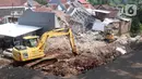 Alat berat berada di rumah yang hancur tertimpa tanah longsor di Perumahan Nerada Estate Ciputat, Tangerang Selatan, Sabtu (12/6/2021). Tidak ada korban jiwa dalam peristiwa longsor yang menimpa sejumlah rumah akibat hujan deras yang terus menerus di kawasan tersebut. (Liputan6.com/Angga Yuniar)