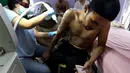 Pria bernama Taufiq Hidayat membaca Alquran Surat Arrahman di telepon genggamnya saat tato ditubuhnya dihapus di Tangerang (9/8). (AP Photo/Achmad Ibrahim)