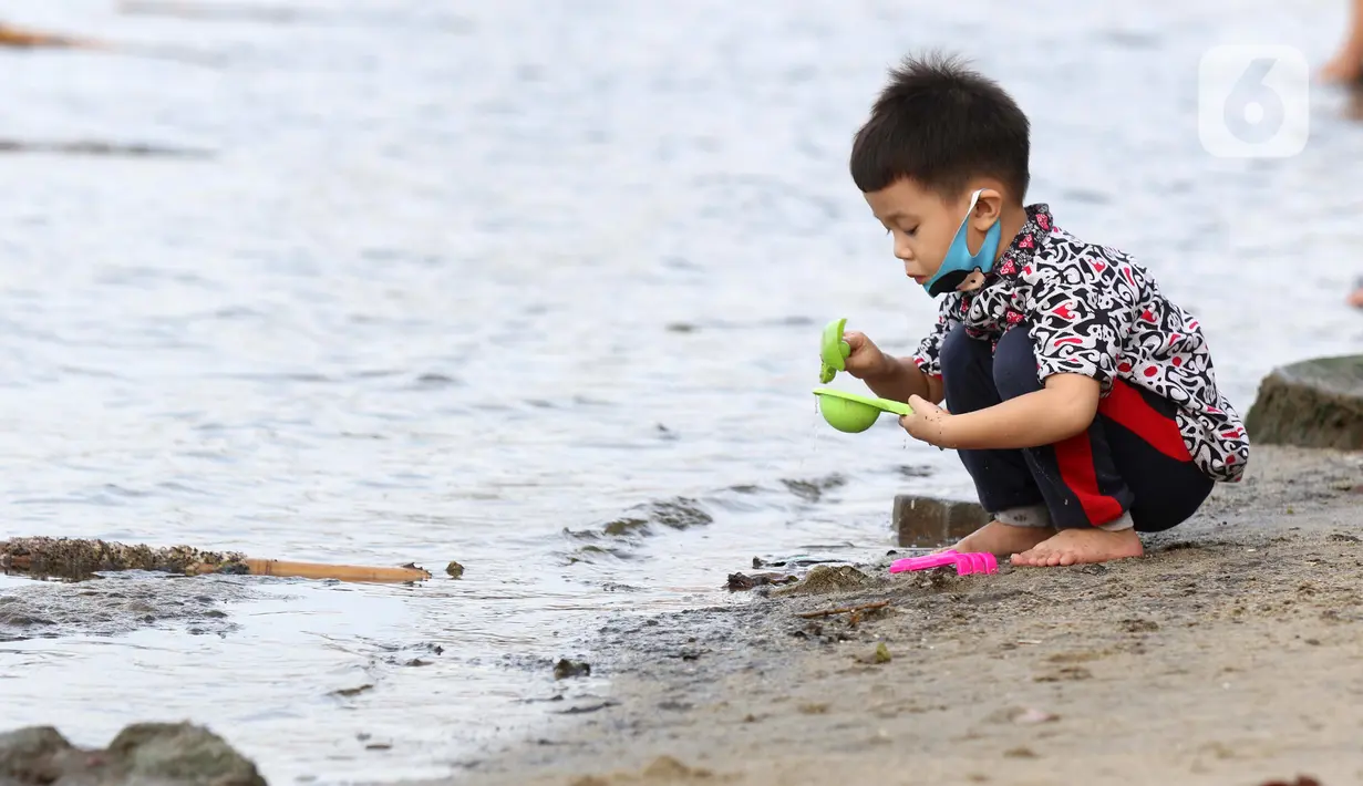 Anak-anak bermain pasir di Pantai Indah Taman Impian Jaya Ancol, Jakarta, Kamis (29/10/2020). Libur panjang di masa pemberlakuan PSBB transisi Jakarta dimanfaatkan warga untuk mengunjungi lokasi-lokasi wiisata. (Liputan6.com/Helmi Fithriansyah)