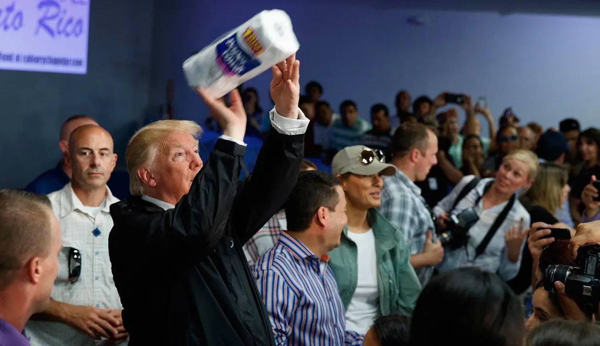Presiden AS Donald Trump melemparkan gulungan handuk kertas kerumunan warga yang terkena dampak badai maria di Kapel Calvary, Puerto Rico, Selasa (3/10). Trump meninjau dan melihat kerusakan yang diakibatkan Badai Maria dua pekan lalu. (AP/Evan Vucci)