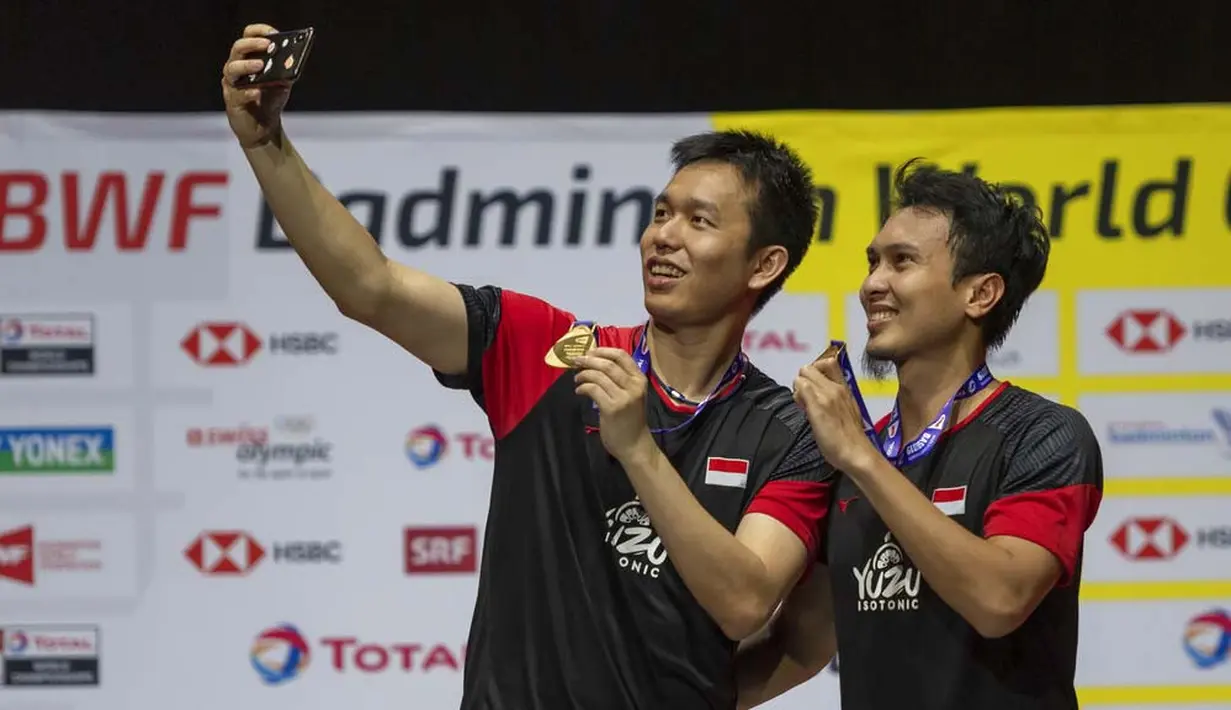 Pasangan Indonesia, Hendra Setiawan/Mohammad Ahsan melakukan swafoto usai menjuarai Kejuaraan Dunia Bulutangkis 2019 setelah mengalahkan wakil Jepang, Takuro Hoki/Yugo Kobayashi, Minggu (25/8). Indonesia menang 25-23, 9-21, 21-15. (AP/Georgios Kefalas)