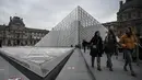 Pengunjung mengantre di luar Pyramid, pintu masuk utama menuju museum Louvre, di Paris, Rabu (4/3/2020). Louvre di Paris, museum yang paling banyak dikunjungi di dunia, kembali dibuka setelah pegawai yang khawatir dengan penularan virus corona setuju kembali masuk kerja. (Philippe LOPEZ/AFP)
