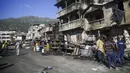 Petugas pemadam kebakaran berdiri dekat bangkai truk pengangkut BBM yang terbalik dan meledak di Cap-Haitien, Haiti, 14 Desember 2021. Ledakan tersebut menghanguskan mobil dan rumah serta menewaskan puluhan orang. (AP Photo/Joseph Odelyn)