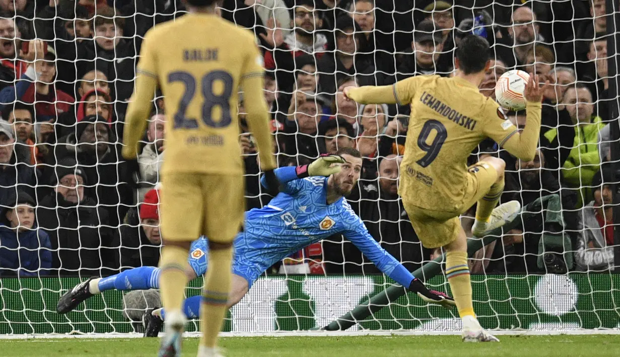 Striker Barcelona, Robert Lewandowski (kanan) menendang bola dari titik penalti yang membuahkan gol dalam pertandingan leg kedua play-off babak gugur Liga Europa 2022/2023 melawan Manchester United yang berlangsung di Old Trafford, Jumat (24/2/2023) WIB. (AFP/Oli Scarff)