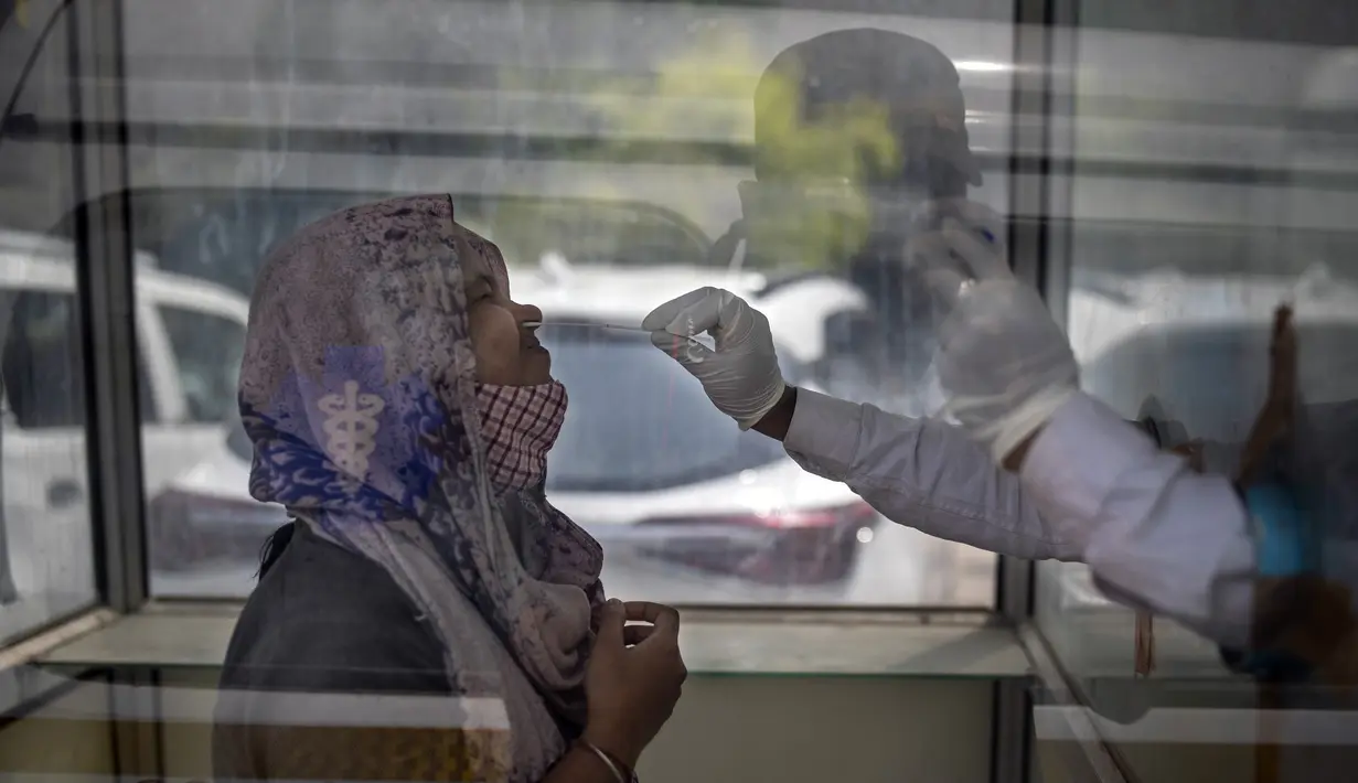 Seorang petugas kesehatan mengambil sampel usap untuk menguji COVID-19 di rumah sakit pemerintah di Noida, pinggiran New Delhi, India, Rabu (7/4/2021). India mencapai puncak baru dengan 115.736 kasus COVID-19 dalam 24 jam. (AP Photo/Altaf Qadri)