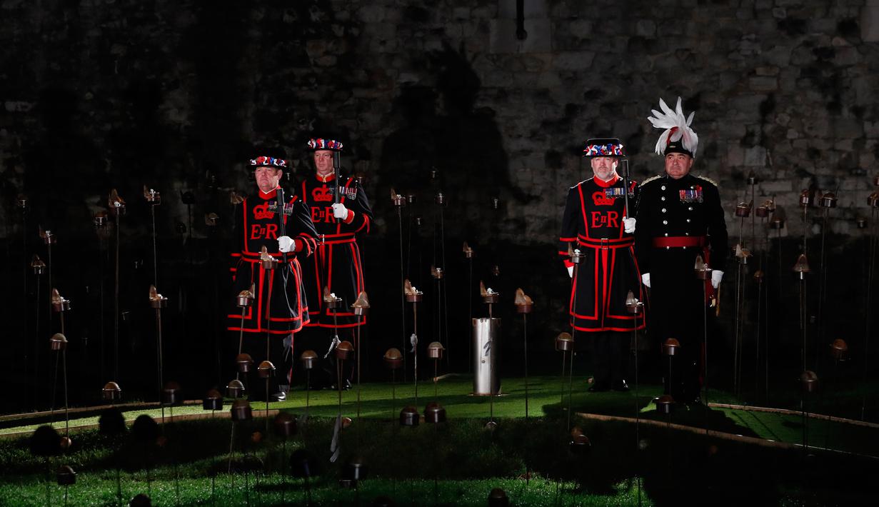 Yeoman Warders atau 'Beefeaters' bersiap menyalakan ribuan lilin di parit kering Tower of London, Inggris, Selasa (6/11). Nyala lilin membentuk instalasi yang disebut 'Beyond the Deepening Shadow: The Tower Remembers'. (AP Photo/Alastair Grant)