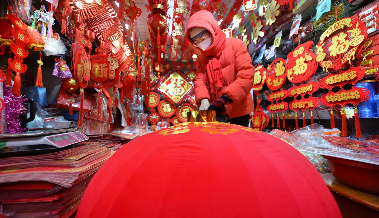 Seorang pedagang menyiapkan lampion merah untuk dijual menjelang Hari Tahun Baru di sebuah pasar di Qingdao, di provinsi Shandong timur China pada 25 Desember 2022. Warga China mulai berburu pernak-pernik Tahun Baru seperti lampion, kartu tahun baru, baju, dan hiasan rumah. (AFP/China Out)