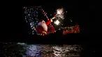 Seorang pria mengenakan kostum Santa Claus bermain kembang api di atas kapal selama perayaan malam Natal di Imperia, Italia (24/12). (AP Photo/Antonio Calanni)