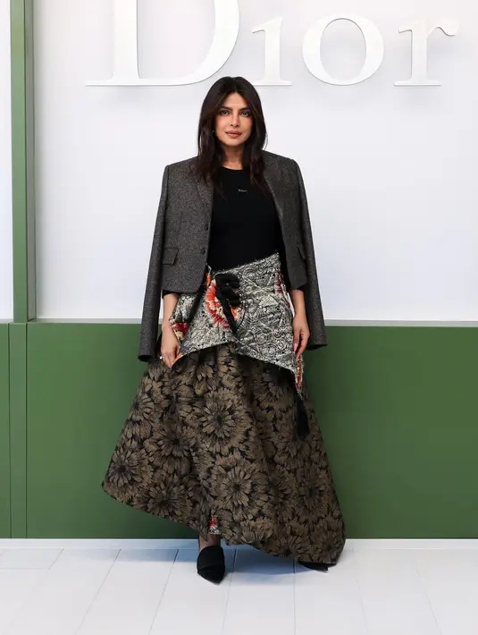 Priyanka Chopra tampil sophisticated dalam balutan jaket wol abu-abu yang dipadukan dengan atasan katun hitam serta rok sutra bermotif warna-warni. Ia juga mengenakan aksesori Dior untuk menyempurnakan gayanya.[Image Credit: Getty Images/DIOR]