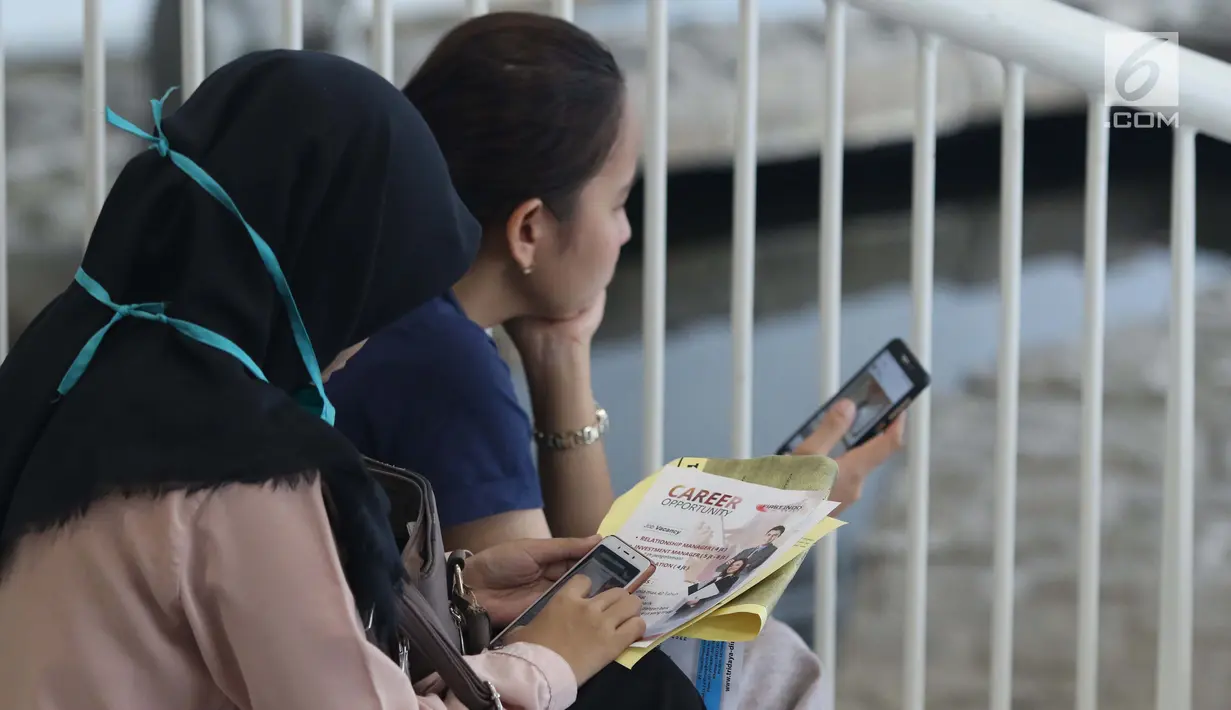 Pencari kerja melihat-lihat ponsel saat gelaran Job For Career Festival 2019 di area Stadion GBK, Jakarta, Selasa (5/3). Berdasarkan data BPS per Agustus 2018 sebanyak tujuh juta orang Indonesia menganggur. (Liputan6.com/Helmi Fithriansyah)