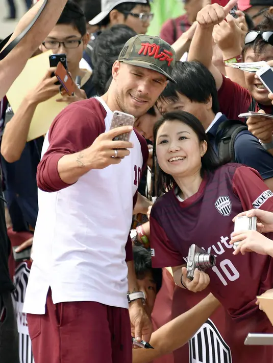 Eks pemain Arsenal, Lukas Podolski berselfie dengan penggemar saat upacara penyambutan di Kobe, Jepang barat, (6/7). Vissel Kobe kabarnya membayar €2,6 juta guna menebus Penyerang berusia 32 tahun ini. (Tsuyoshi Ueda/Kyodo News via AP)