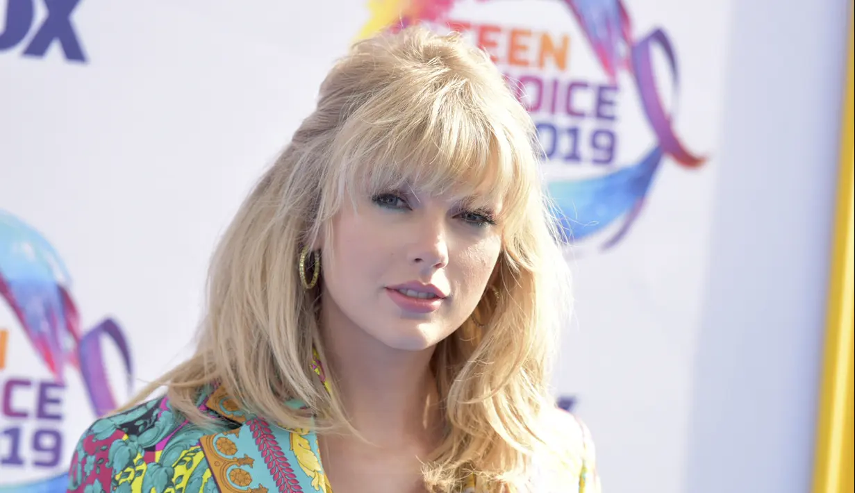 Taylor Swift berpose menghadiri FOX's Teen Choice Awards 2019 di Hermosa Beach, California (11/8/2019). Taylor mengguncang ansambel bermotif Versace yang menampilkan kombinasi kancing baju dan celana pendek yang serasi, yang memperlihatkan bra berenda merahnya. (AP Photo/Richard Shotwell)