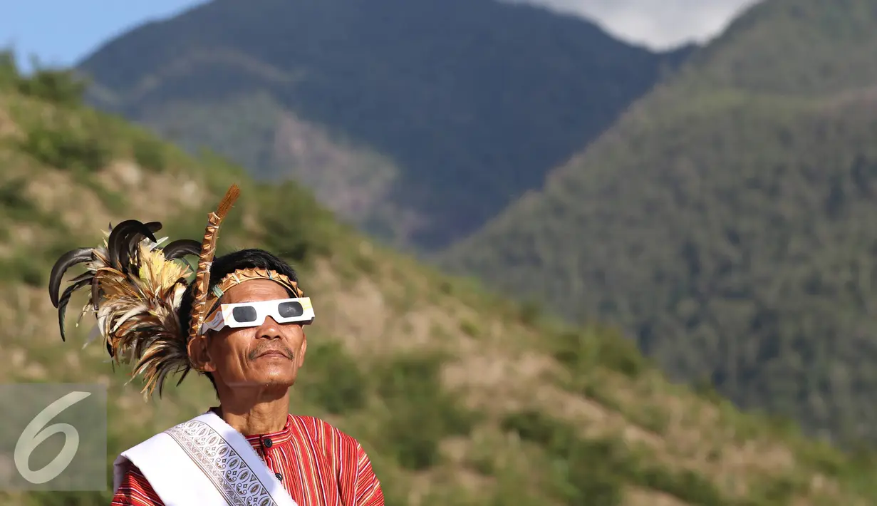 Seniman memakai kacamata melihat gerhana matahari di Bukit Matantimali, Sigi, Sulawesi Tengah, Rabu (9/3). Tarian tersebut dilakukan dalam rangka menyambut gerhana matahari total serta menolak bala. (Liputan6.com/Immanuel Antonius)