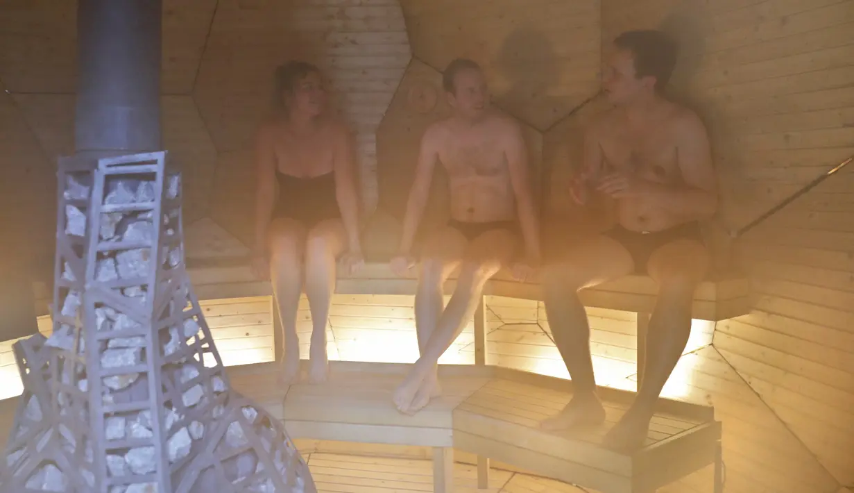 Pengunjung menikmati sauna berbentuk telur raksasa keemasan bernama Solar Egg di halaman Institut Swedia di Paris, Rabu (15/11). Bagian interiornya, terbuat dari batu, kayu, kuningan, dan kaca, lengkap dengan LED dan panel surya. (PATRICK KOVARIK / AFP)