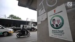 Poster pasangan Cagub dan Cawagub Jawa Barat Ridwan Kamil-Uu Ruzhanul Ulum terpampang di kolong tol kawasan Kalimalang, Bekasi, Minggu (24/6). Meski telah memasuki masa tenang Pilkada 2018, alat peraga kampanye masih terpampang.(Merdeka.com/Iqbal Nugroho)