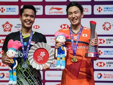 Tunggal putra Indonesia, Anthony Ginting, naik podium bersama tunggal Jepang, Kento Momota, pada BWF World Tour 2019 di Tianhe Gymnasium, Guangzhou, Minggu (15/12). Ginting kalah 21-17, 17-21 dan 14-21 dari Momota. (AFP/STR)