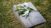 Ilustrasi bunga lili, dukacita. (Photo by Ivan Samkov: https://www.pexels.com/photo/lilies-on-a-tombstone-on-a-green-grass-8963669/)