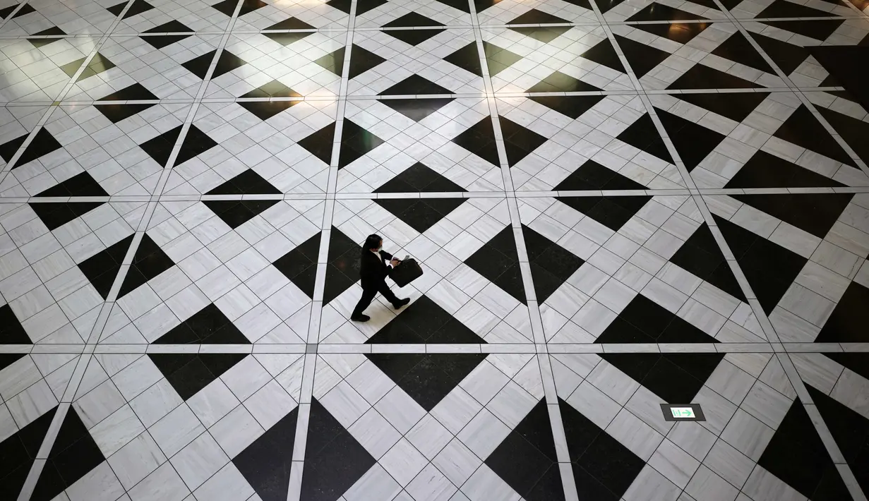 Seorang pria yang mengenakan masker untuk membantu mengekang penyebaran virus corona berjalan di sebuah gedung di Tokyo, Kamis, (27/8/2020). (AP Photo/Eugene Hoshiko)
