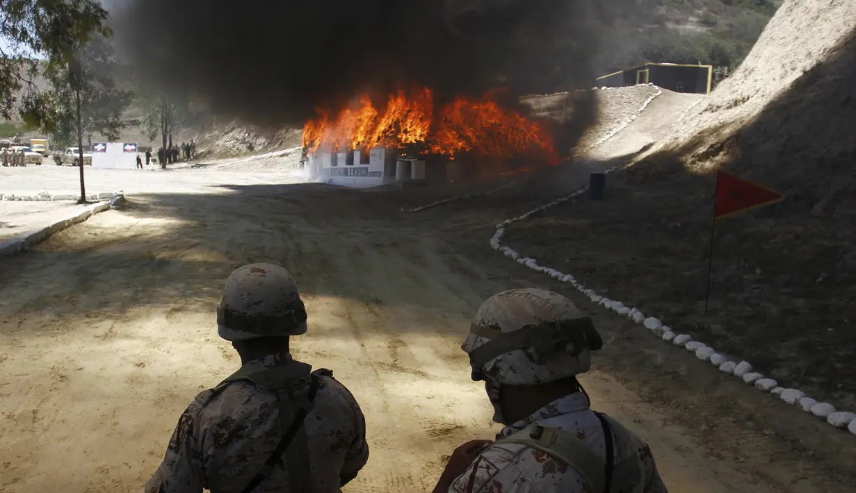 Petugas berjaga saat pembakaran ganja dan obat terlarag lainnya di kamp angkatan darat, Tijuana, Meksiko, (18/8/2015). 7 ton obat terlarang yang disita di Tijuana akan dibakar secara bersamaan di sembilan negara bagian di Meksiko. (REUTERS/Jorge Duenes)