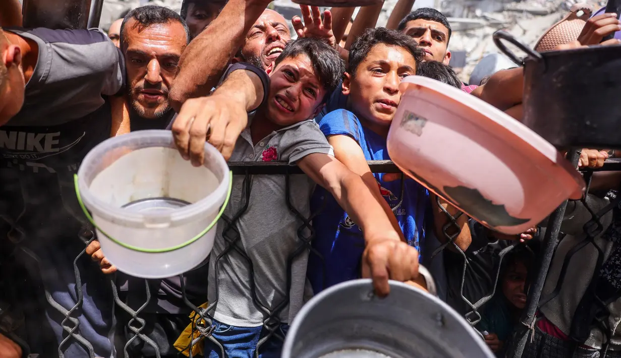 Warga Palestina berdesakan berebut makanan yang sudah dimasak dari dapur umum di Jabalia, Jalur Gaza Utara, pada 17 Mei 2025. (Bashar TALEB/AFP)