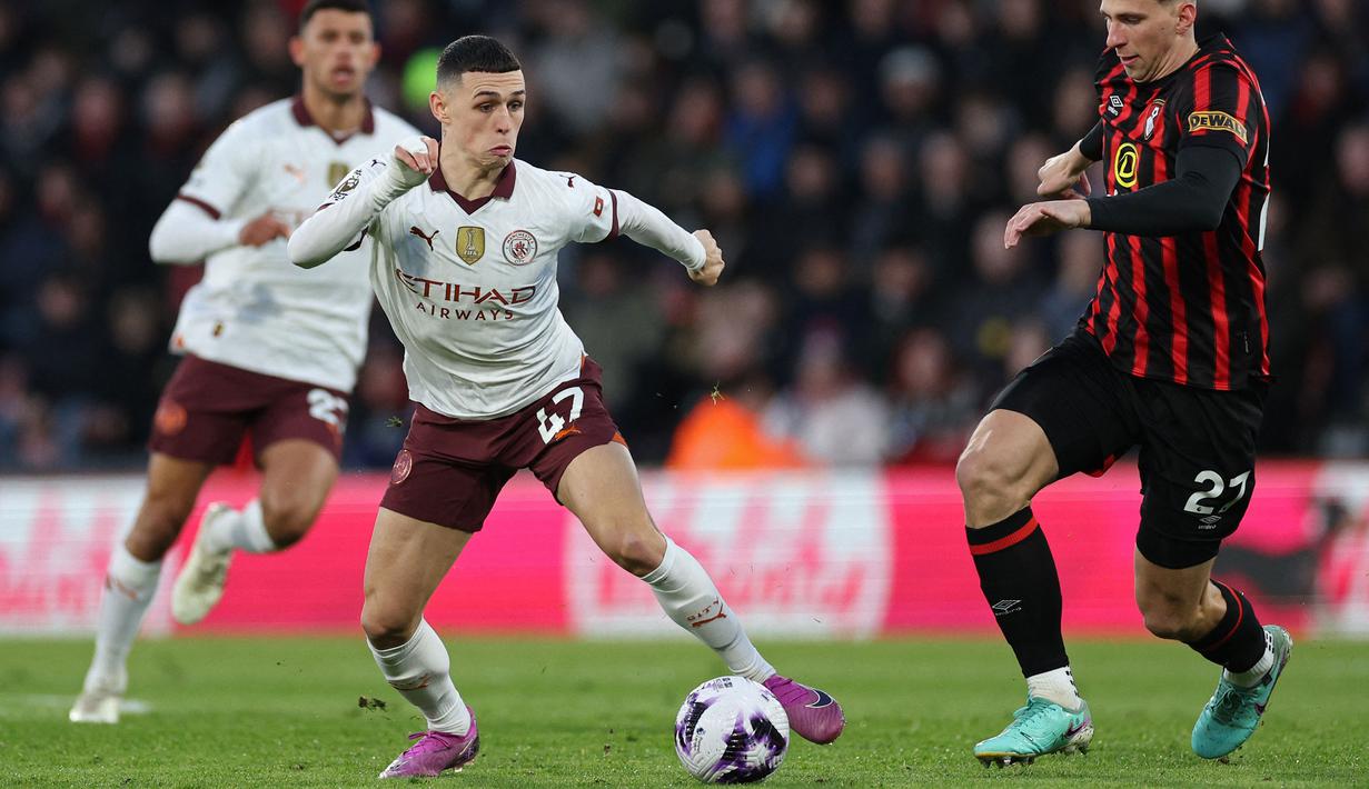 Pemain Manchester City, Phil Foden (kiri) berebut bola dengan pemain Bournemouth, Illia Zabarnyi pada laga lanjutan Liga INggris 2023/2024 yang berlangsung di Vitality Stadium, Bournemouth, Inggris, Minggu (25/02/2024) dini hari WIB. (AFP/Adrian Dennis)