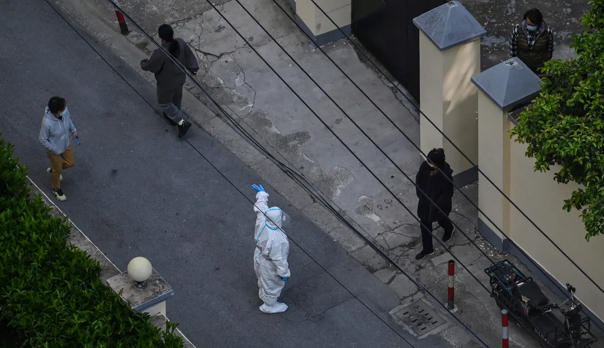 Seorang petugas kesehatan yang mengenakan alat pelindung diri (APD) berbicara dengan penduduk sebuah bangunan perumahan kecil saat lockdown akibat virus corona COVID-19 di Distrik Jing'an, Shanghai, China, Sabtu (16/4/2022). (Hector RETAMAL/AFP)
