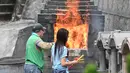 Orang-orang membakar persembahan untuk memberi penghormatan kepada orang tercinta yang telah meninggal di Pemakaman China Cape Collinson, dekat Chai Wan, Hong Kong, 5 April 2021. Kegiatan ini untuk menandai Festival Ching Ming yang juga dikenal sebagai pembersihan makam. (Peter PARKS/AFP)