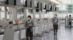 Ground staff bekerja di lobi keberangkatan Bandara Internasional Haneda yang sepi di Tokyo, Senin (28/12/2020). Jepang untuk sementara waktu melarang semua pendatang asing yang bukan penduduk masuk sebagai bentuk antisipasi varian baru COVID-19 hingga akhir Januari 2021. (AP Photo/Koji Sasahara)