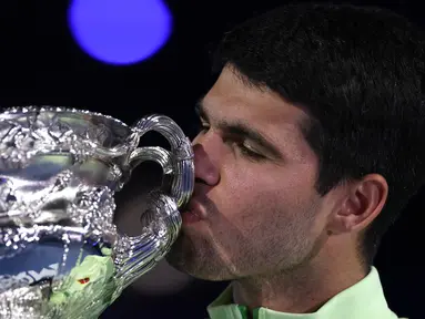 Carlos Alcaraz mencium piala usai berhasil menjuarai Australian Open 2026 setelah menaklukkan Novak Djokovic dalam laga sengit yang dilangsungkan di Melbourne Park pada (1/2/2026) sore WIB. (AFP/Martin Keep)