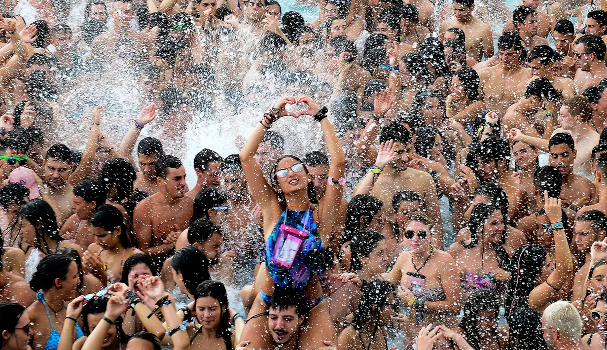 Seorang wanita membuat tanda hati dari tangannya saat berdansa di kolam selama Festival Arenal Sound di Pantai Burriana, Spanyol (2/8). Festival musik enam hari ini menampung sekitar 240.000 orang. (AFP Photo/Jose Jordan)