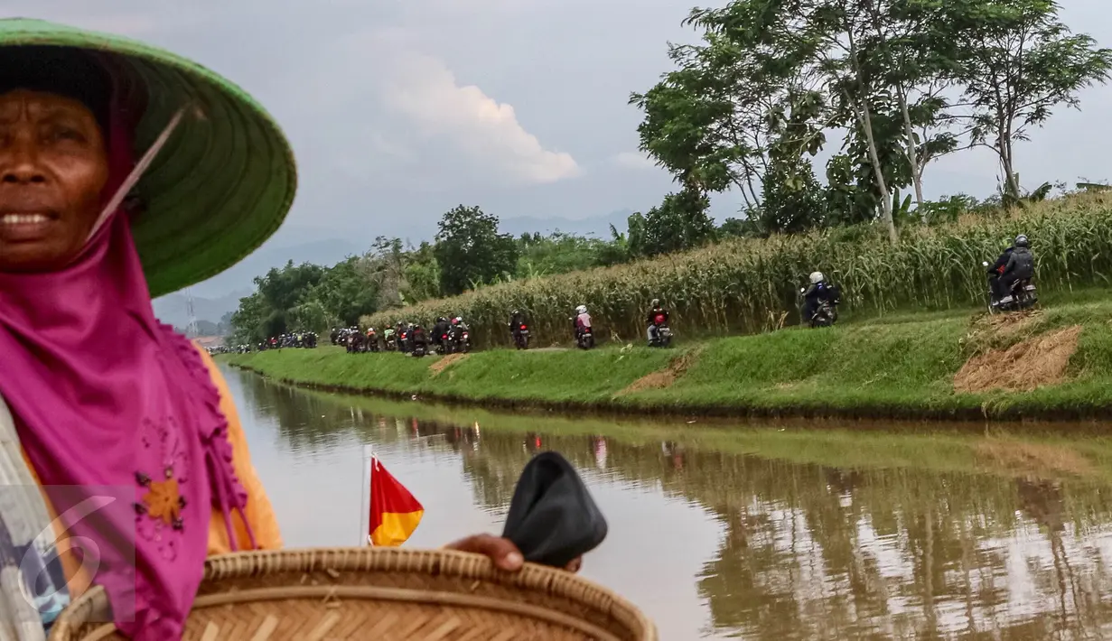 Pemudik motor menerobos jalan perkampungan untuk mengindari kemacetan di kawasan Ketanggungan, Kabupaten Brebes, Jawa Tengah, Senin (4/6). Jalan yang melintasi sepanjang kali ini, menjadi pemandangan bagi pemudik roda empat. (Liputan6.com/Fery Pradolo)
